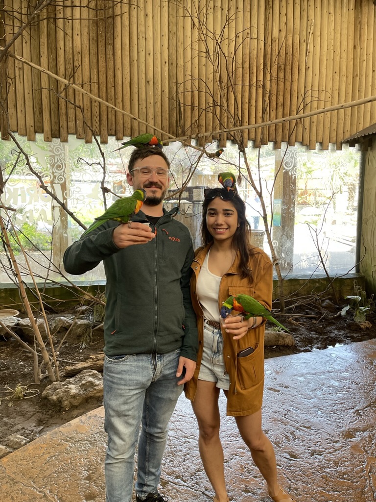Mansi and Chris feeding colourful parrots together