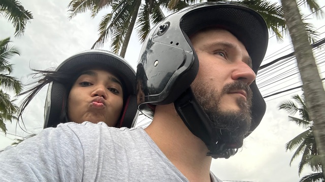 Mansi and Chris wearing scooter helmets beneath palm trees